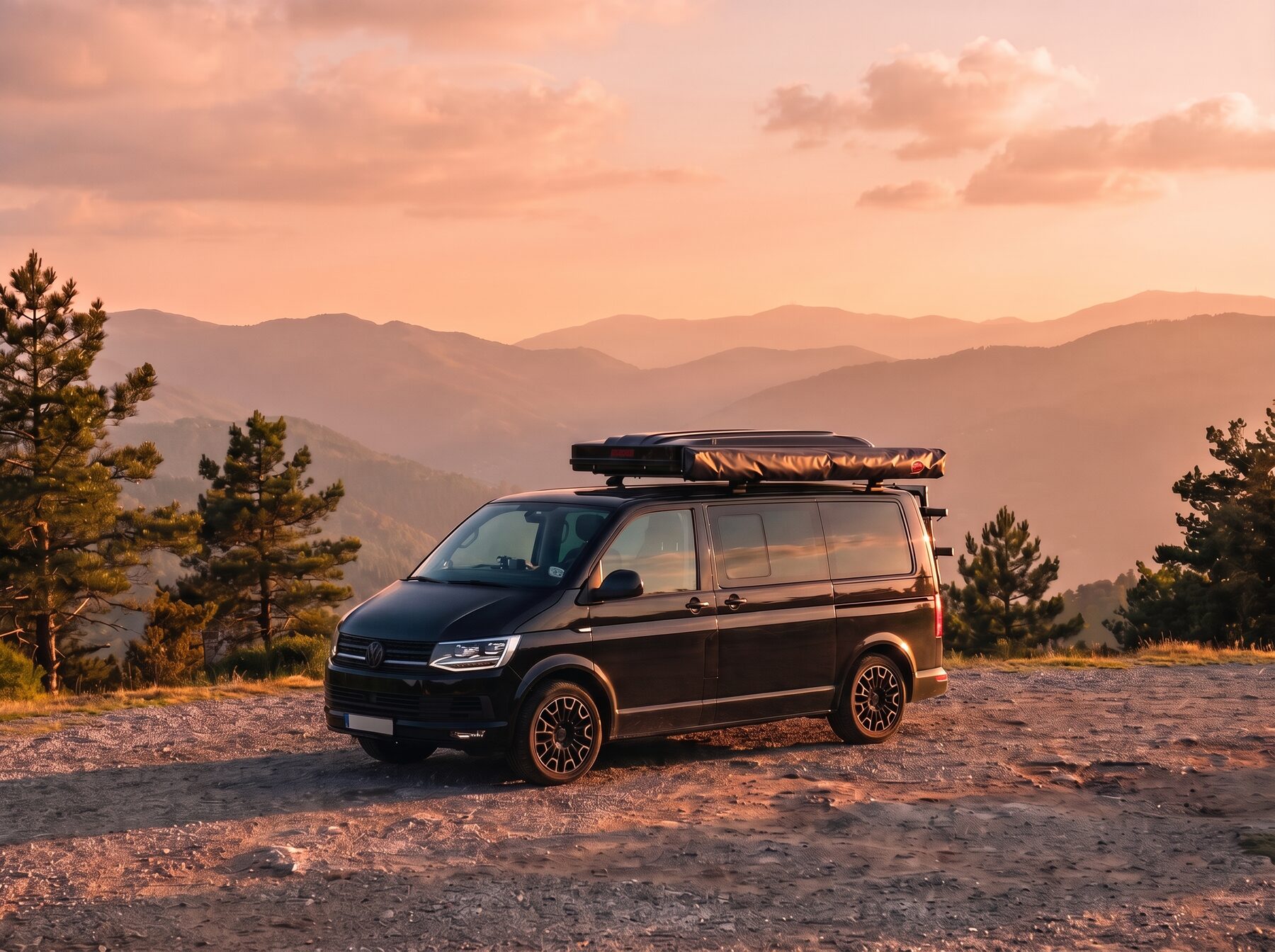 Černá dodávka Volkswagen Transporter se střešním stanem zaparkovaná na horské vyhlídce v podvečerním světle